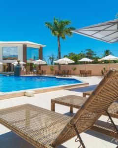 塞古罗港Pontal Praia Hotel的一个带藤椅的游泳池的度假酒店