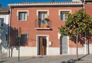 格拉纳达LA CASA DE LOS PINTORES, junto al centro de Granada的前面有棵树的红色建筑