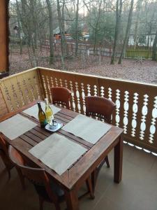 KismarosŐzike-Lak a Börzsönyben的阳台上的木桌和一瓶葡萄酒