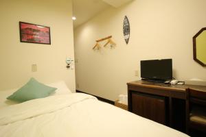 东京Okubo Hotel Hawaii的一间卧室配有一张床和一张书桌及电视