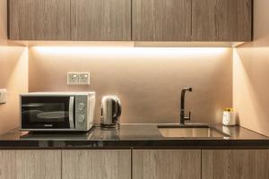 新加坡Hotel Calmo Bugis的厨房柜台配有微波炉和水槽