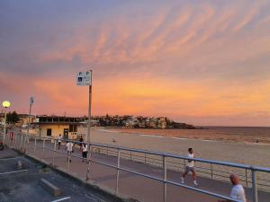 悉尼Bondi Beach Backpackers的一群人日落时在海滩上散步