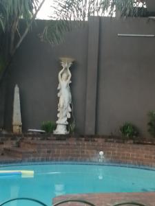 约翰内斯堡Naisar's Apartments Primrose,Johannesburg的游泳池旁的猫雕像