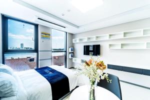江陵市Hi Ocean Gyeongpo的一间卧室,配有一张床,桌子上放着花瓶
