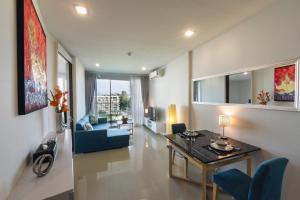 华欣First Choice Grand Suites Sha Plus Extra的客厅配有桌子和蓝色沙发