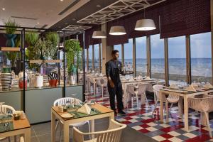 迪拜Riu Dubai Beach Resort - All Inclusive的站在带桌椅的餐厅里的人