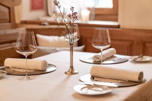 埃布斯Unterwirt - Das kleine Gourmethotel的一张桌子,上面放有两杯酒和一张白桌布