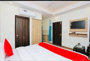 新德里Airport Hotel Golden Bliss Near Delhi Airport的卧室配有红色和白色的床以及平面电视。