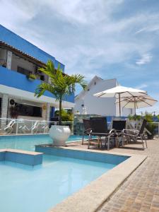 里约达欧特拉斯马雷西亚科斯塔阿苏尔旅馆的一座带椅子和遮阳伞的游泳池位于一座建筑旁边