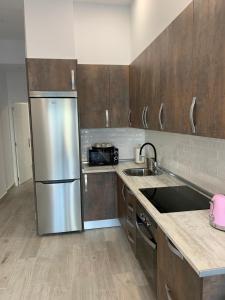 马德里T-Homes - Fuencarral的厨房配有不锈钢冰箱和木制橱柜
