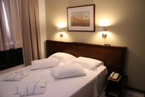 马林加Golden Ingá Hotel的一张带两个白色枕头的床和电话