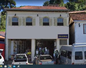 欧鲁普雷图Vila Marias的一座白色的建筑,前面有汽车停放