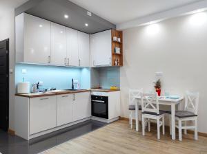 罗兹Apartamentylove - Apartament Kiliński的厨房配有白色橱柜和桌椅