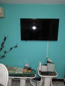 欧丘里欧Cool's 1 bedroom Beach & Garden View的蓝墙上的电视,配有桌椅