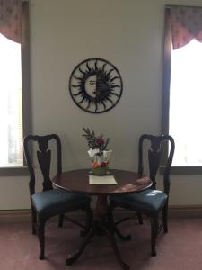 杰纳西奥橡树谷住宿加早餐旅馆的餐桌、两把椅子和墙上的时钟