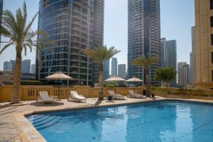 迪拜Suha JBR Hotel Apartments的城市里一个带椅子和遮阳伞的游泳池