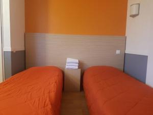 豪森HECO Colmar Nord - ex Première Classe的小客房内的两张床,配有橙色床单