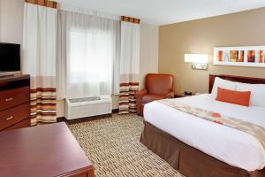 布鲁艾施MainStay Suites Cincinnati Blue Ash的酒店客房带一张大床和一把椅子