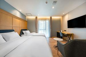 釜山Brown Dot Hotel Signature的酒店客房设有两张床和一台平面电视。