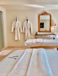 圣雷米普罗旺斯勒瓦隆德瓦鲁格温泉酒店的卧室配有挂在墙上的长袍和镜子