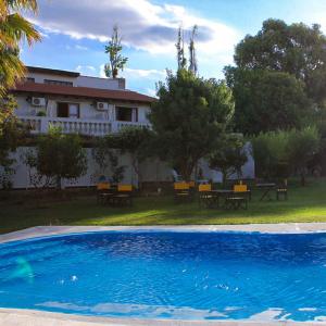 卢汉德库约De Los Andes Hotel Boutique的一座带桌子和长凳的房屋前的游泳池