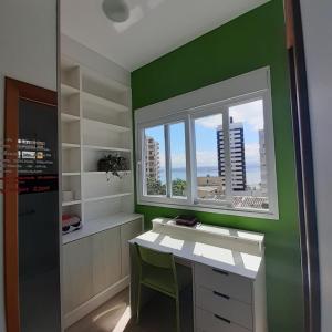弗洛里亚诺波利斯Suíte confortável的绿色的客房设有书桌和窗户。