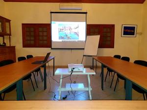 格雷岛Villa Charles - île de Gorée的一间会议室,配有两张桌子和投影屏幕