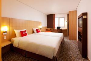 首尔ibis Ambassador Seoul Insadong的酒店客房配有一张带红色枕头的大床