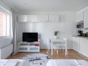 约恩苏Kotimaailma Apartments Joensuu - Koulukatu 21的一间白色的厨房,内设一张桌子和一台电视机。