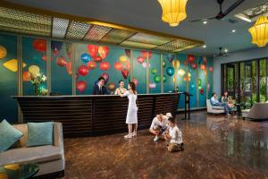 会安Bel Marina Hoi An Resort的大厅里有一个女人和两个孩子,墙上有气球