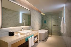 天津天津中北假日酒店的一间带水槽、浴缸和镜子的浴室