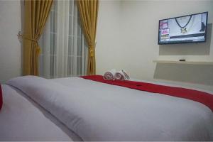 玛琅RedDoorz near Araya Family Club House的一间卧室设有一张带平面电视的床。
