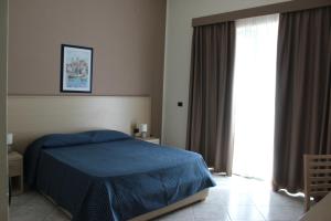切法卢旅游酒店的一间卧室设有蓝色的床和大窗户