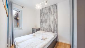 尤斯托尼莫斯基Apartamenty Sun & Snow Dwie Sosny z sauną的一间卧室配有一张带白色床单的床和一扇窗户。