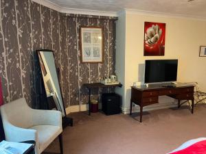 韦茅斯The Kingswood Guest House - Adult Only的客厅配有电视、书桌和椅子