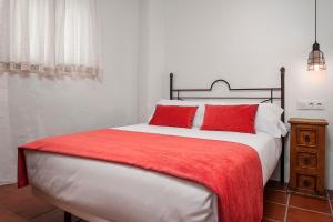 科尼尔-德拉弗龙特拉Habitaciones y Apartamentos en el centro La Jábega by Conil Home的一间卧室配有一张带红色枕头的大床