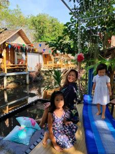 洛坤府Nakhon Si Ban Na Homestay的两个小女孩坐在泳池旁的木筏上