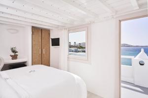 米克诺斯城Little Venice Suites的白色的卧室设有床和窗户