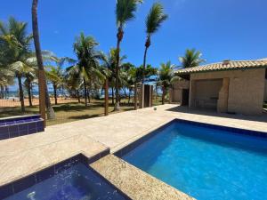 萨尔瓦多Casa Tropical pé na areia的一座棕榈树游泳池和一座房子