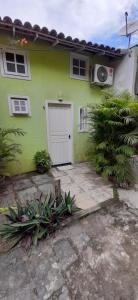 阿布拉奥Loft e Vila da Praia Studios Ilha Grande的一座绿色的房子,有白色的门和一些植物