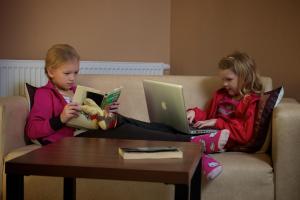 特伦钦温泉镇维拉安娜酒店的两个小女孩坐在沙发上,手提电脑