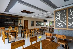 库塔The Calna Villa Bali的餐厅设有木桌和椅子以及大墙