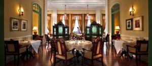 马六甲The Majestic Malacca Hotel - Small Luxury Hotels of the World的一间设有白色桌椅和窗户的用餐室