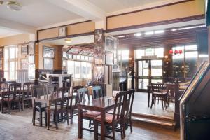 伦敦OYO The Green Man Pub And Hotel的餐厅设有木桌、椅子和窗户。