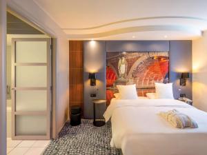 图卢兹图卢兹中心美居酒店的酒店客房设有两张床,墙上挂有绘画作品