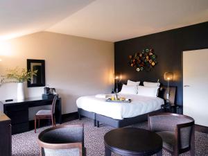 梅斯La Citadelle Metz MGallery的酒店客房带一张床、一张桌子和椅子