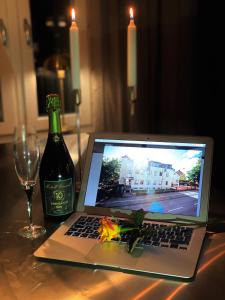 韦克舍瓦润德酒店的坐在桌子旁的一台笔记本电脑,旁边放一瓶葡萄酒