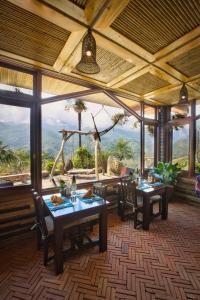 萨帕生态棕榈屋 - 萨帕度假村的一间带桌椅的用餐室和大窗户