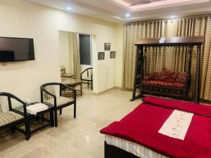 穆扎法拉巴德Thikana Hotel的一间卧室配有一张床、一台电视和一张沙发