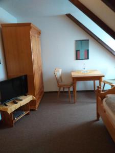 巴特贝尔卡Pension Töpferhof的客房设有桌子、电视、桌子和椅子。